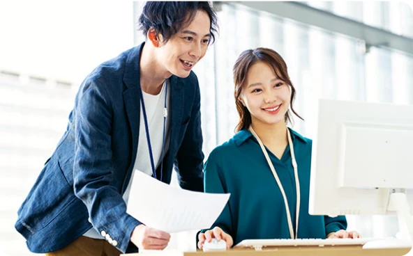 パソコン画面を見ながらメンバー間で連携するビジネスパーソン